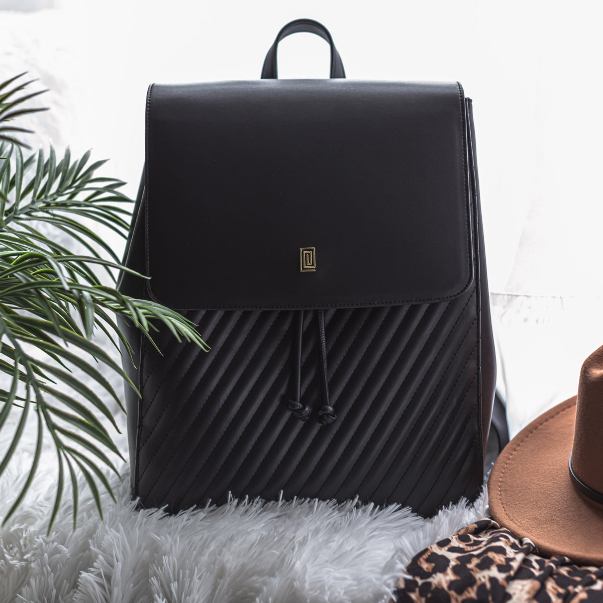Black quilted vegan leather drawstring backpack with palm leaves.