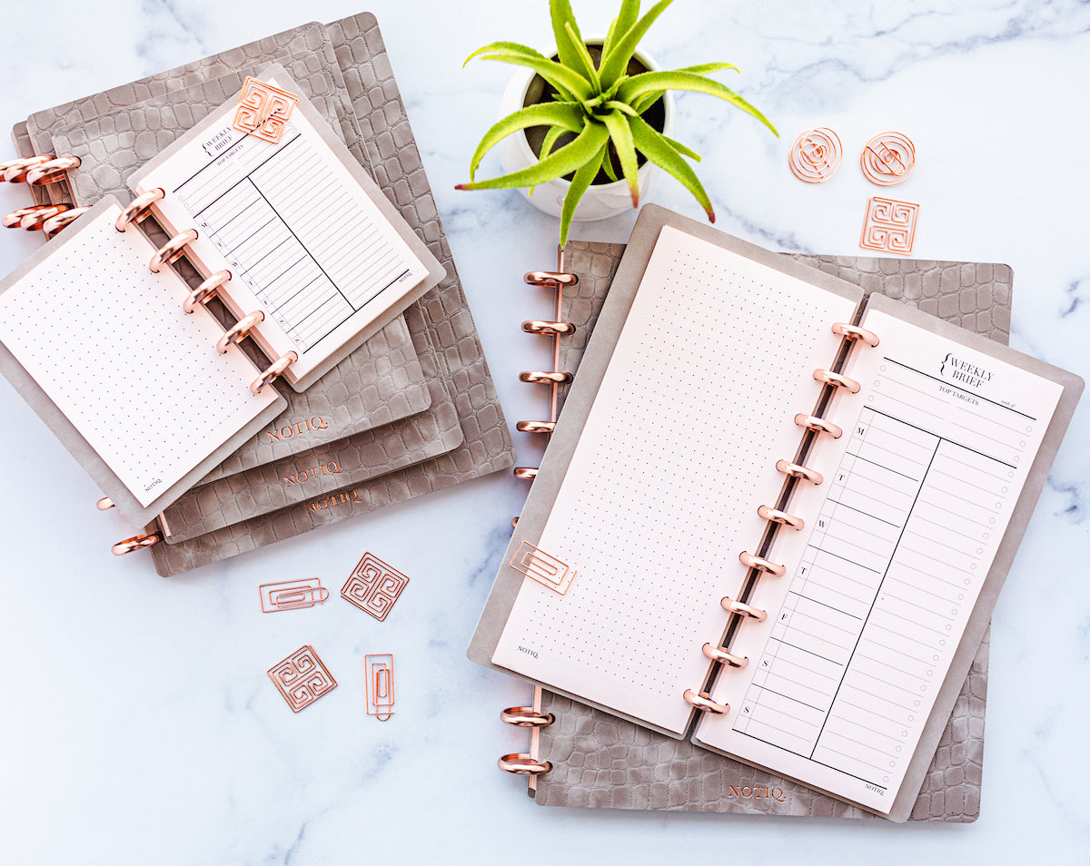 Two stacks of gray vegan leather discbound notebooks open on a desk.