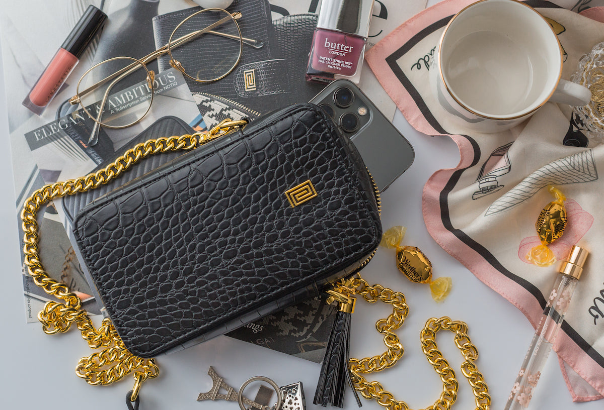 A black croco vegan leather phone bag resting on a magazine.