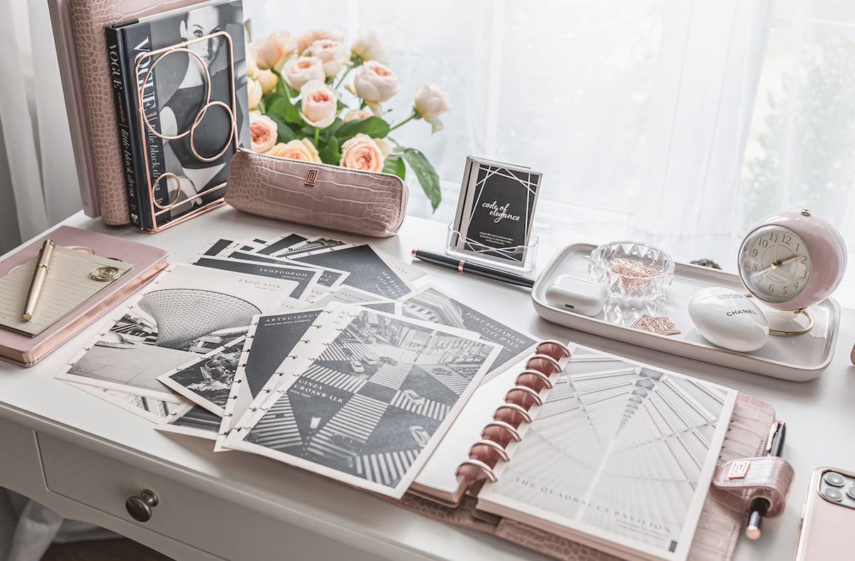 Black and white planner inserts with travel landmarks spread across agenda on desk.