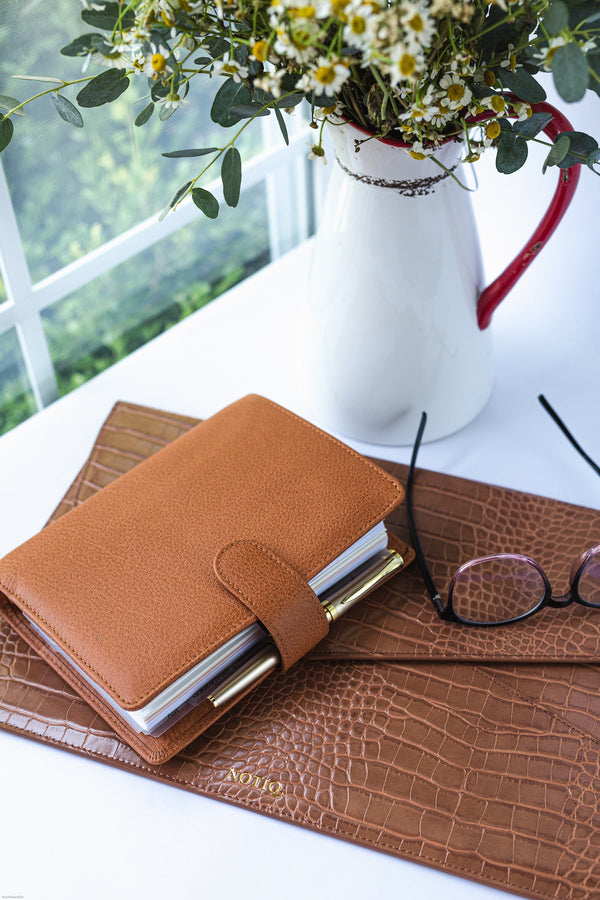 A brown leather planner and a vegan leather laptop case.
