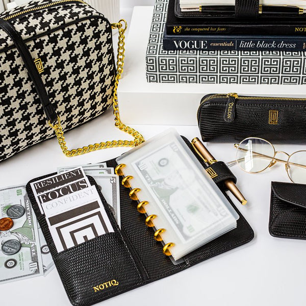 Luxury finance agenda open on office desk with houndstooth bag and black lizard pencil case.