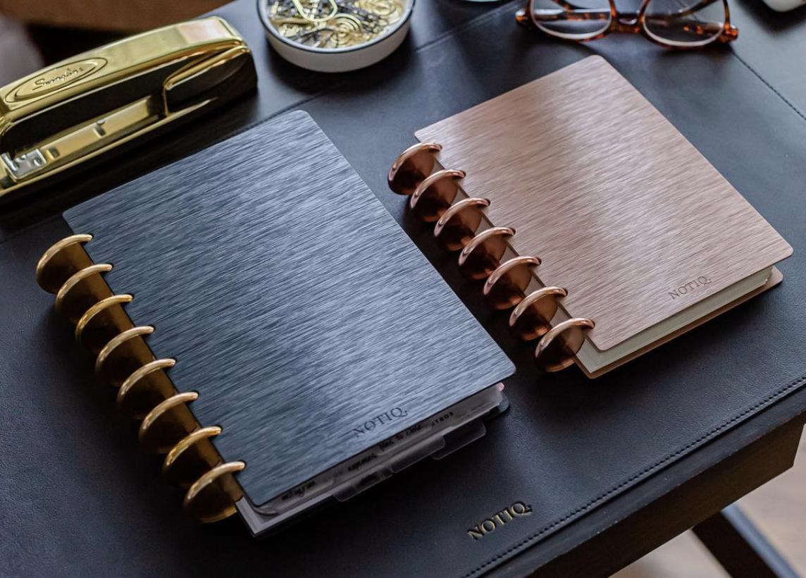 Luxury black and rose gold discbound notebooks on a desk.