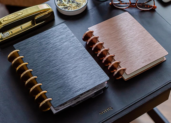 Luxury black and rose gold discbound notebooks on a desk.